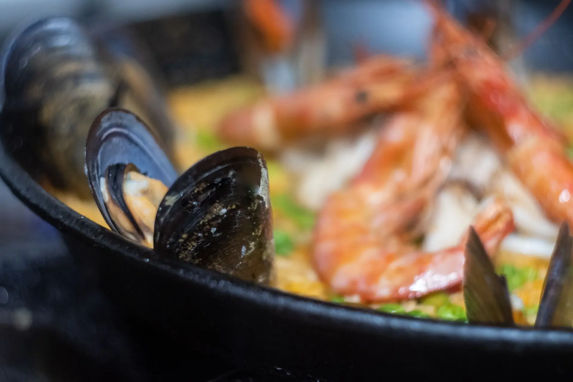 Este vibrante primer plano de una paella española tradicional resalta sus ricas texturas y sabores intensos, con mariscos perfectamente cocidos, arroz infusionado con azafrán y hierbas frescas. Capturada por Louis Mas, fotógrafo y videógrafo culinario en Barcelona, esta imagen es ideal para marketing digital, branding gastronómico y narrativas culinarias.
